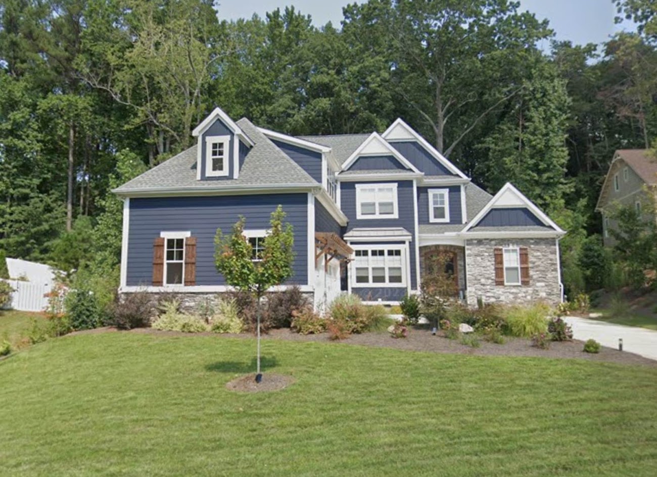 A blue two-storey home in daylight before any lighting