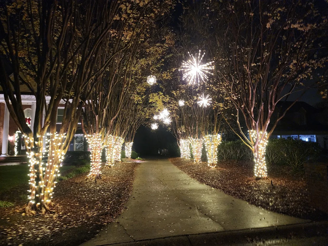 Warm white Christmas lights following a long driveway and roofline