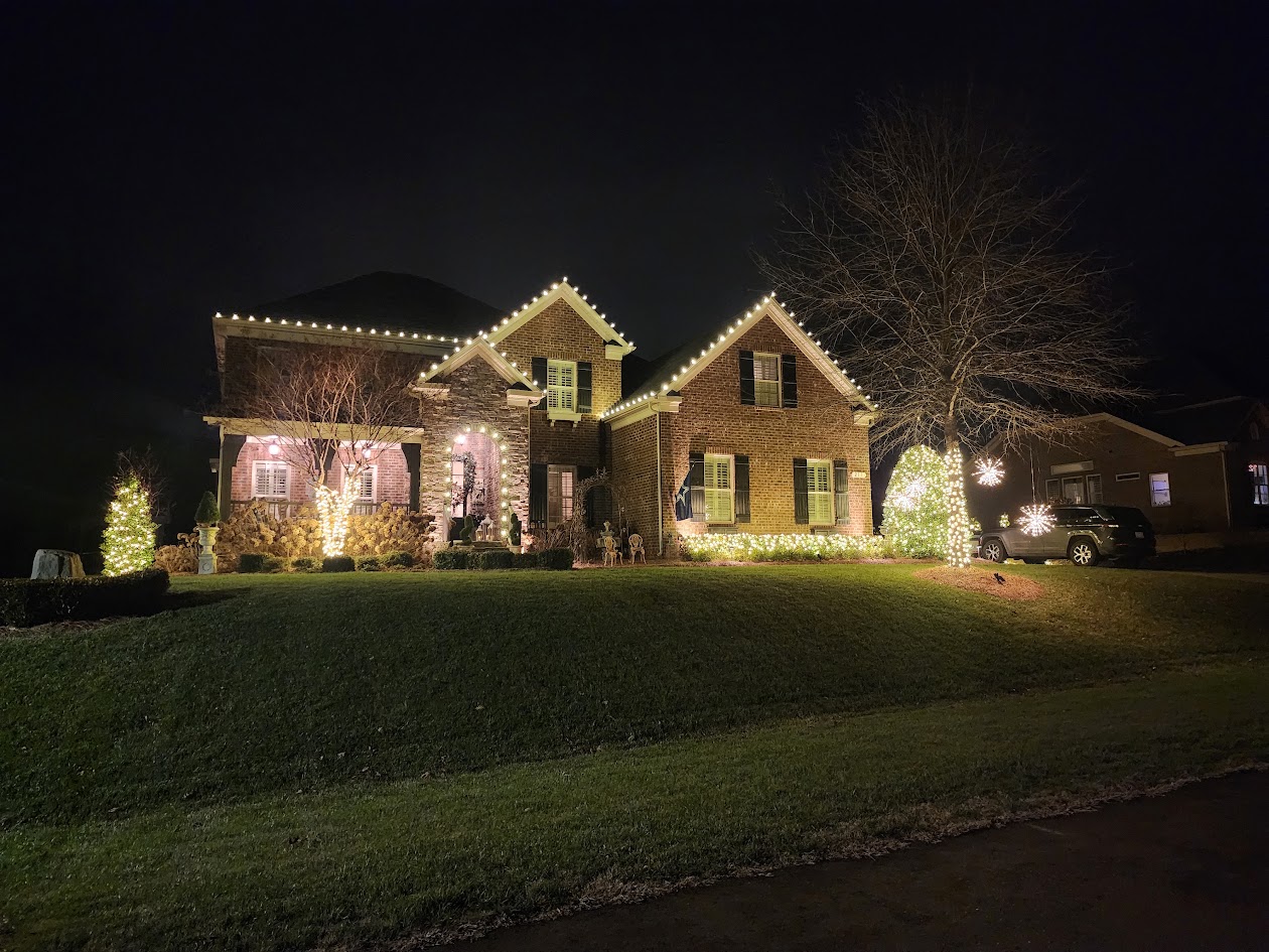 Warm white roofline, tree, and starburst lighting on a Davidson home