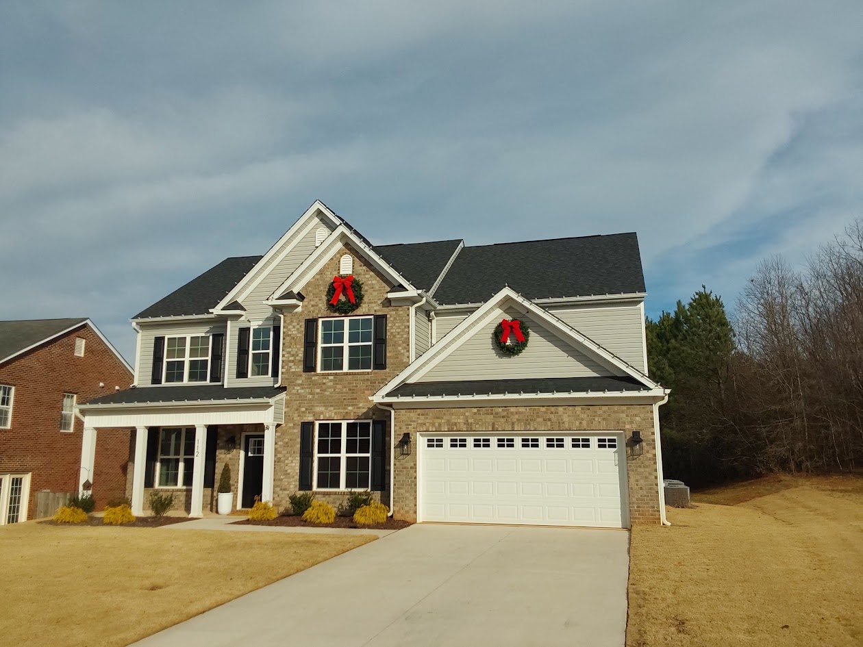 Two large wreaths installed on the upper gables of a Troutman home