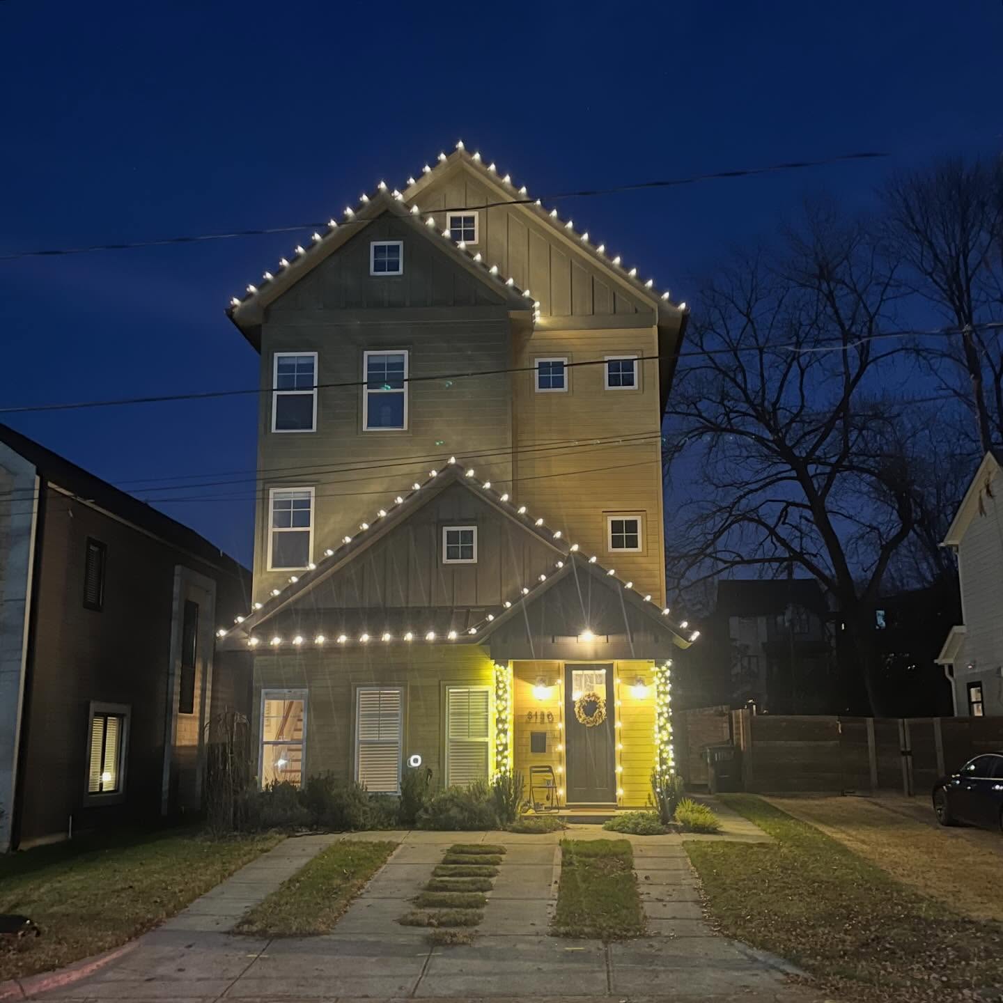 Warm white roofline, column, and entry lighting on a Plaza Midwood home