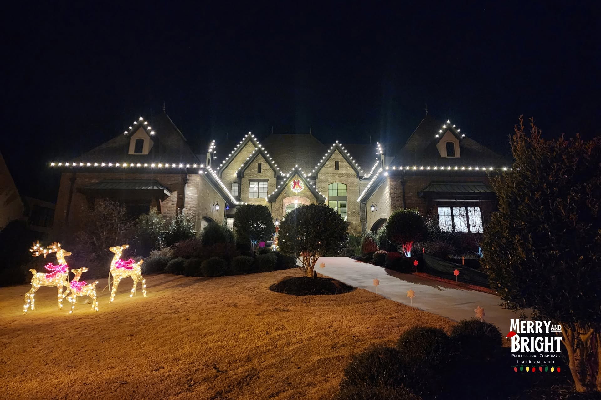 Warm white roofline lighting, greenery, and reindeer on a Waxhaw home
