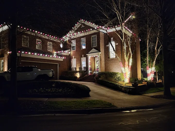 Red and warm white roofline and tree lighting on a brick home