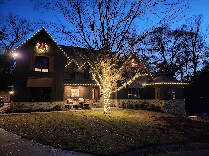 Warm white roofline and tree lighting on a large home
