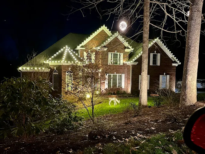 Warm white lighting along rooflines, ridges, and a turret