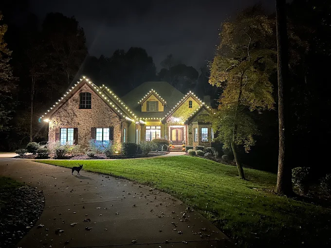 Warm white roofline lighting on a stone-front home