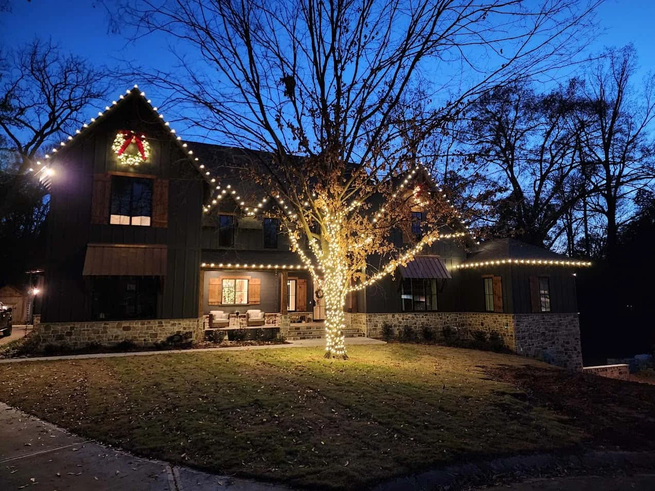 Warm white Christmas lights on a roofline and mature front-yard tree